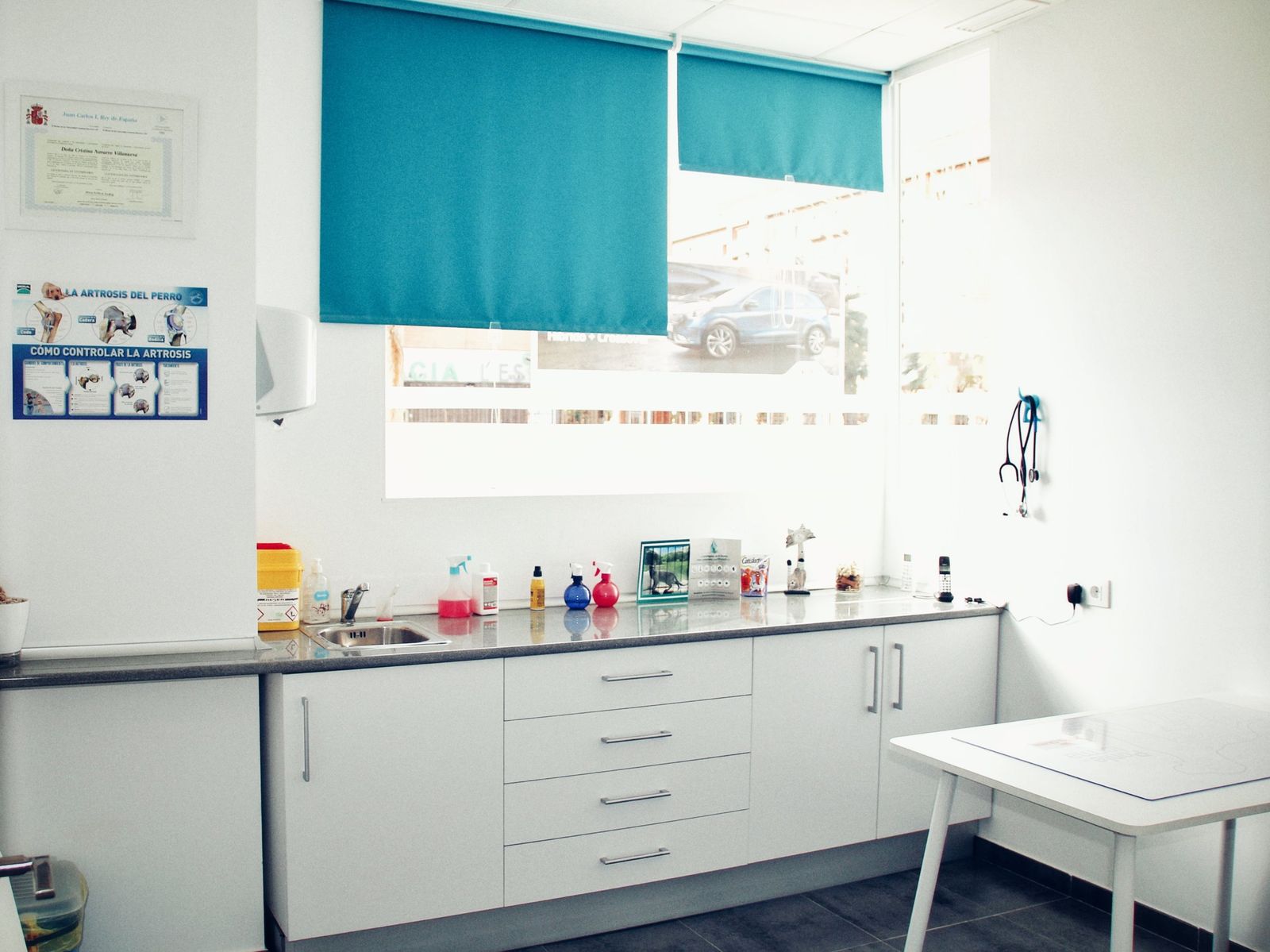 Una sala de consulta luminosa, con persianas azules y mesa de exploración